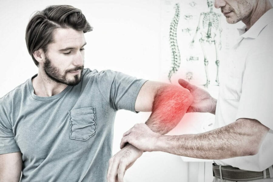 male physiotherapist examining the red, swollen left elbow of a male patient