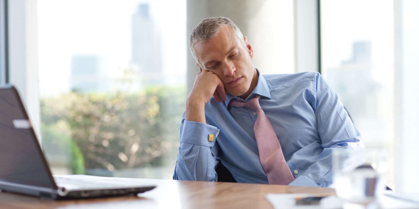Man in business attire falling asleep at a desk