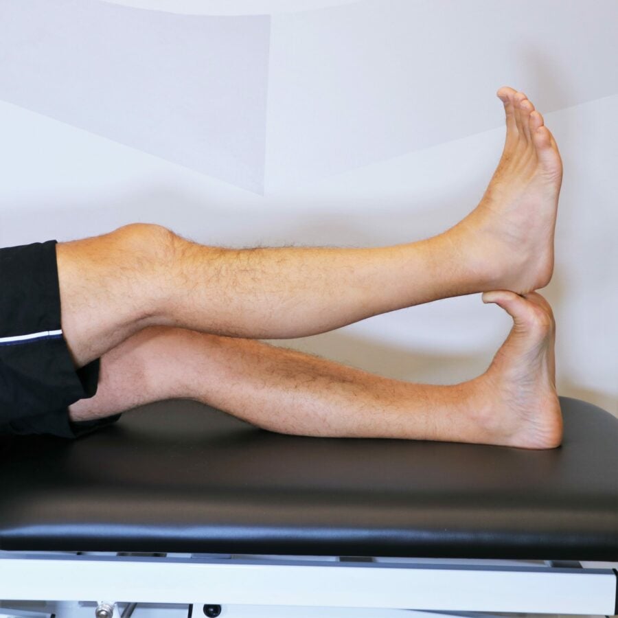 legs shown in a lying position with one leg being used to stretch the plantar fasciia of the other leg