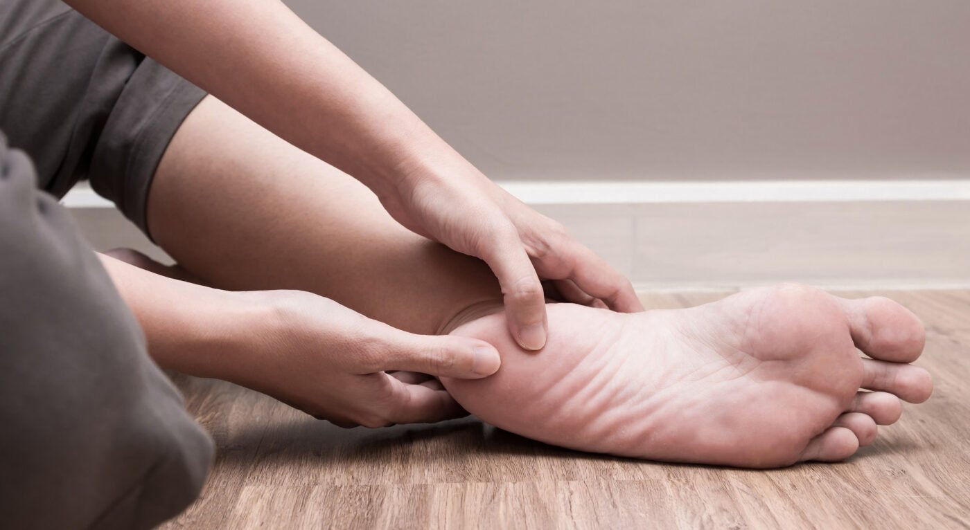 personal holding her heel in pain due to plantar fasciitis