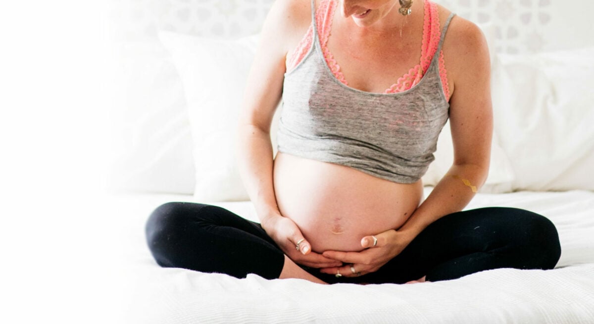pregnant woman holding belly while seated