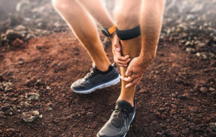 Male runner holding shin in pain due to shin splints