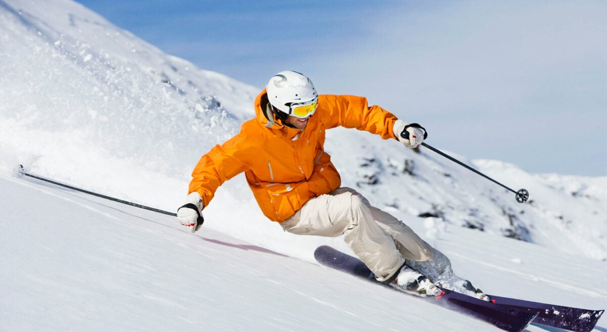 man skiing downhill in orange jacket