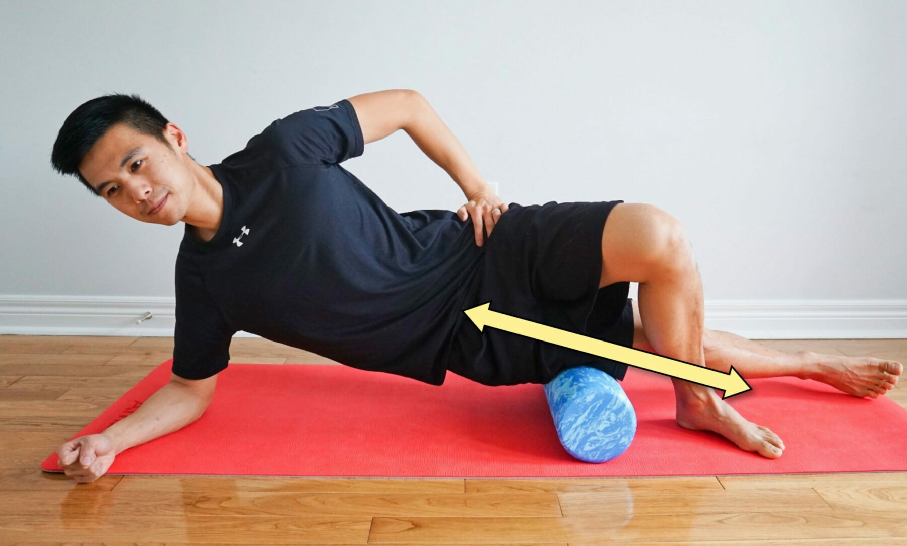 man streching his IT band while side-lying on a roller