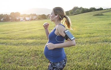 pregnant woman running jogging in a field